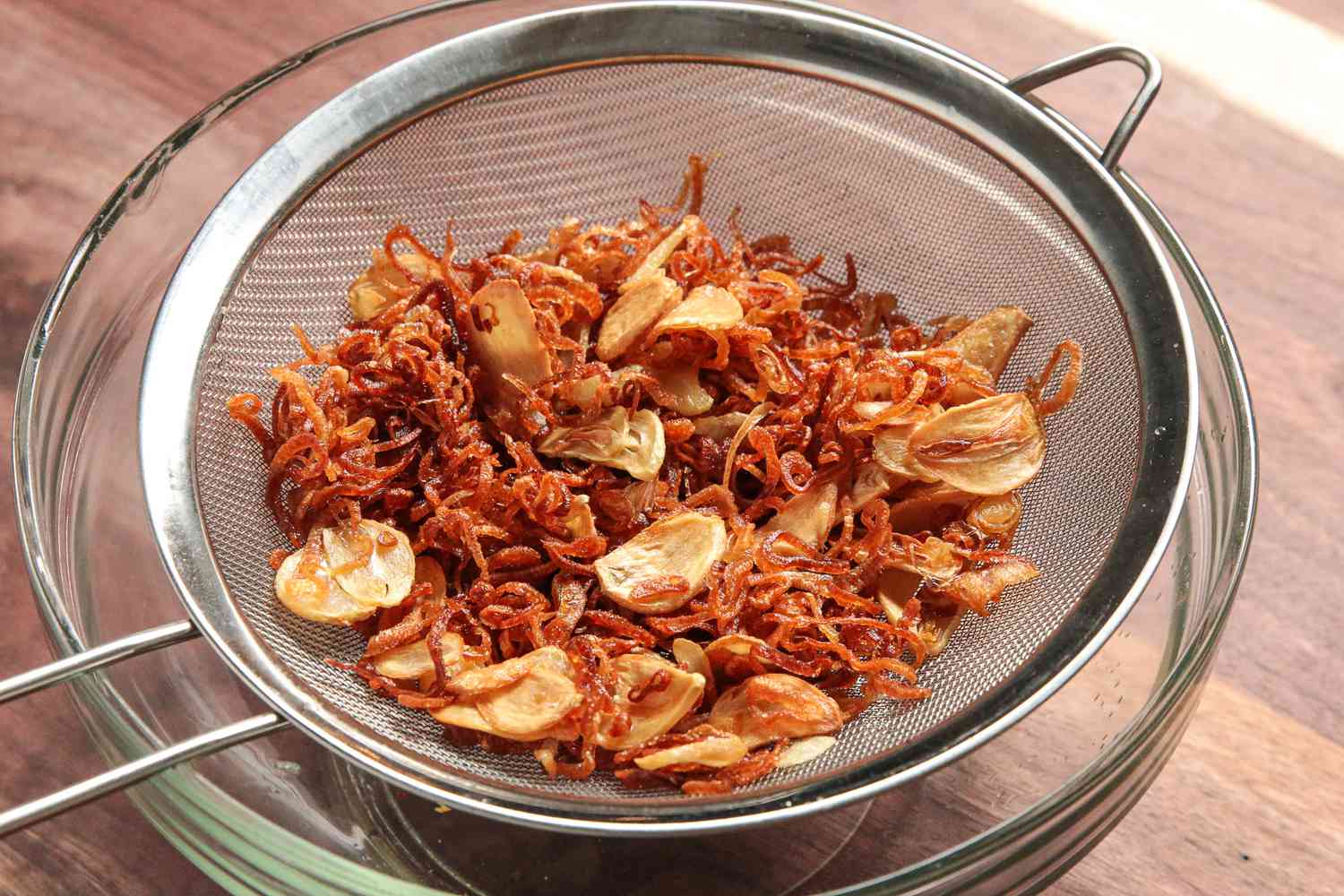 Golden Brown Fried Garlic and Shallots in a Sieve Over a Bowl