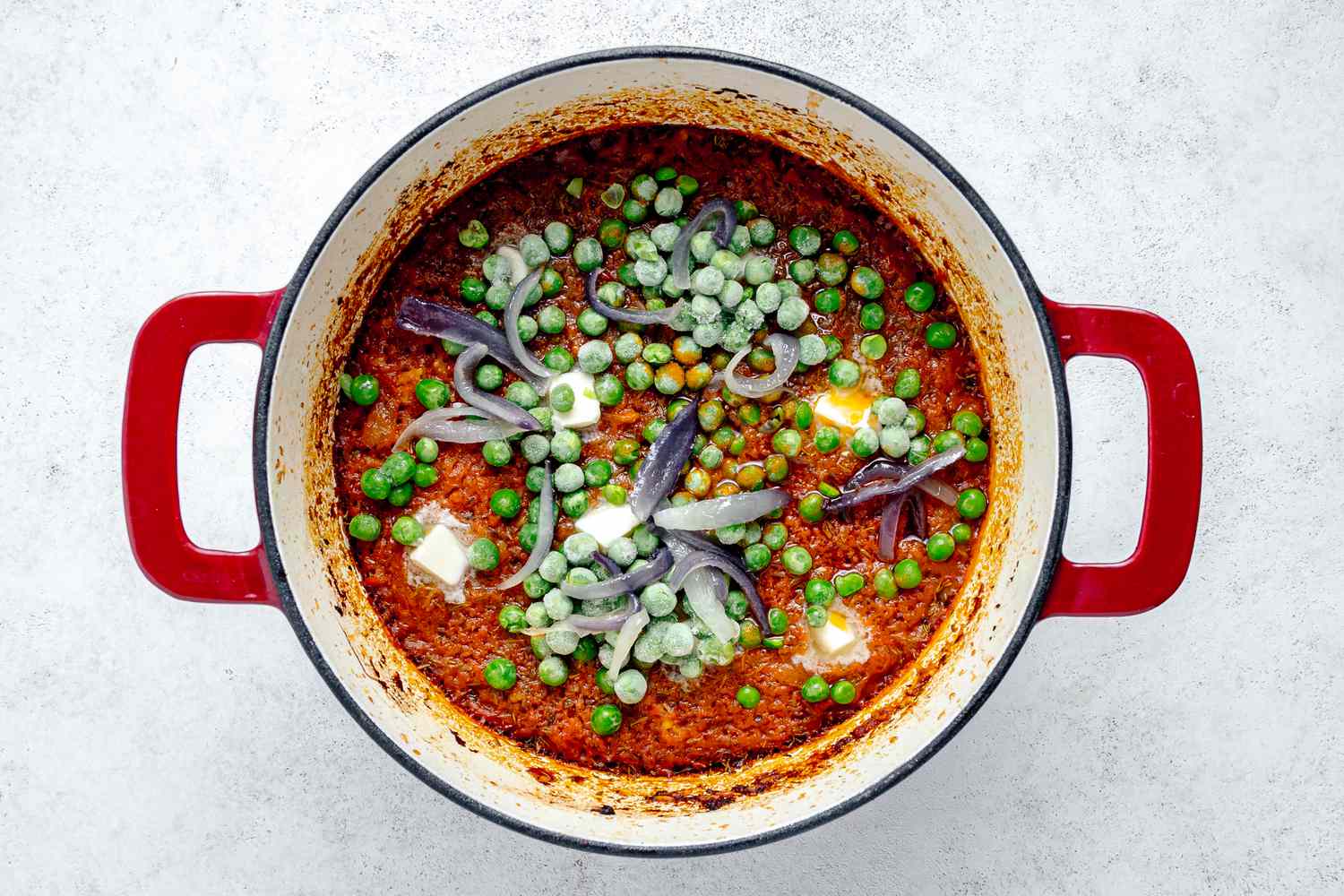 Fried Onions, Butter, and Frozen Peas Added to Pot of Jollof Rice