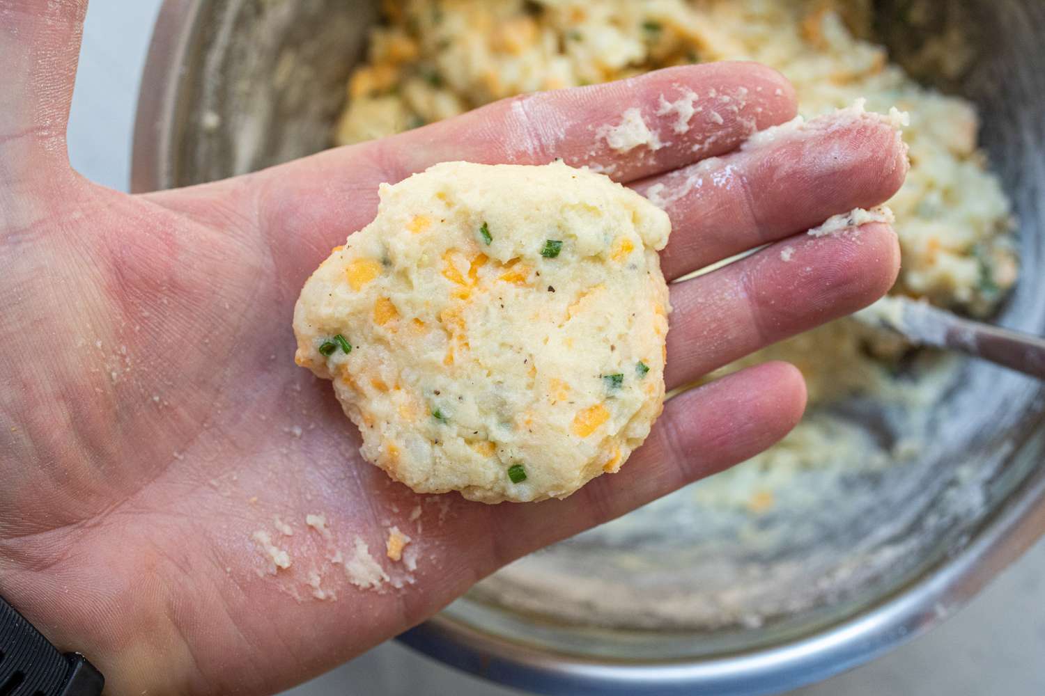 Patting filling into pancakes to make mashed potato pancakes with cheddar.
