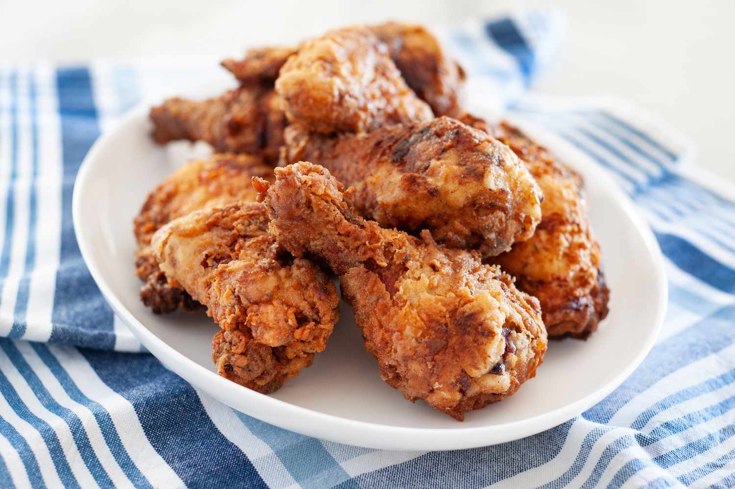 Side view of fried chicken breast stacked on a platter.