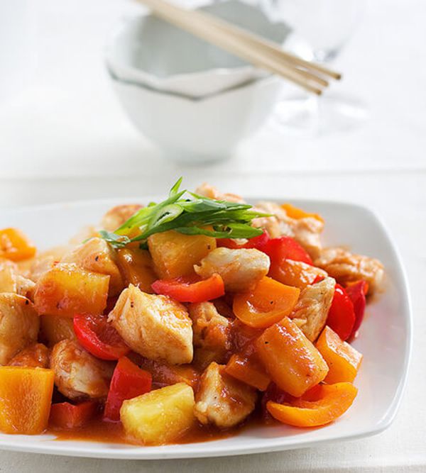 Sweet Sour Chicken on a white plate with chopsticks in the background
