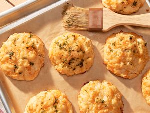 Copycat Red Lobster cheddar bay biscuits on a baking sheet with a pastry brush 