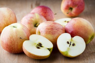 Various whole and halved apples arranged on a wooden surface