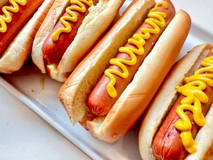 Four hot dogs in buns each topped with mustard