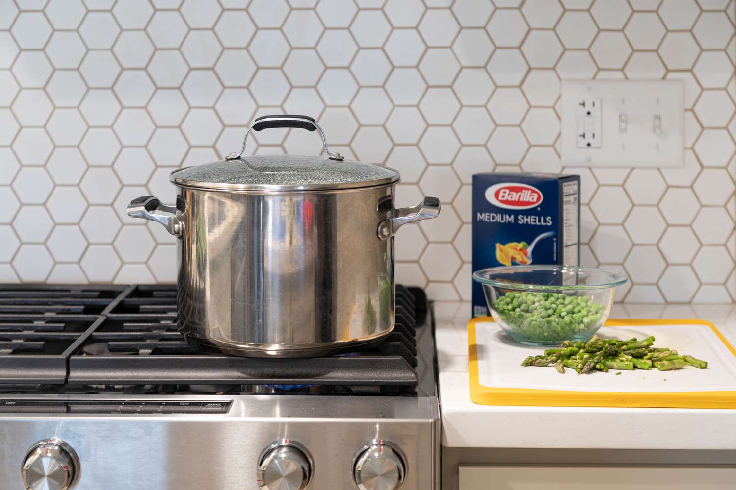 Pot of Boiling Water on Stove Next to a Cutting Board with Asparagus and Bowl of Peas for Green Goddess Pasta Salad