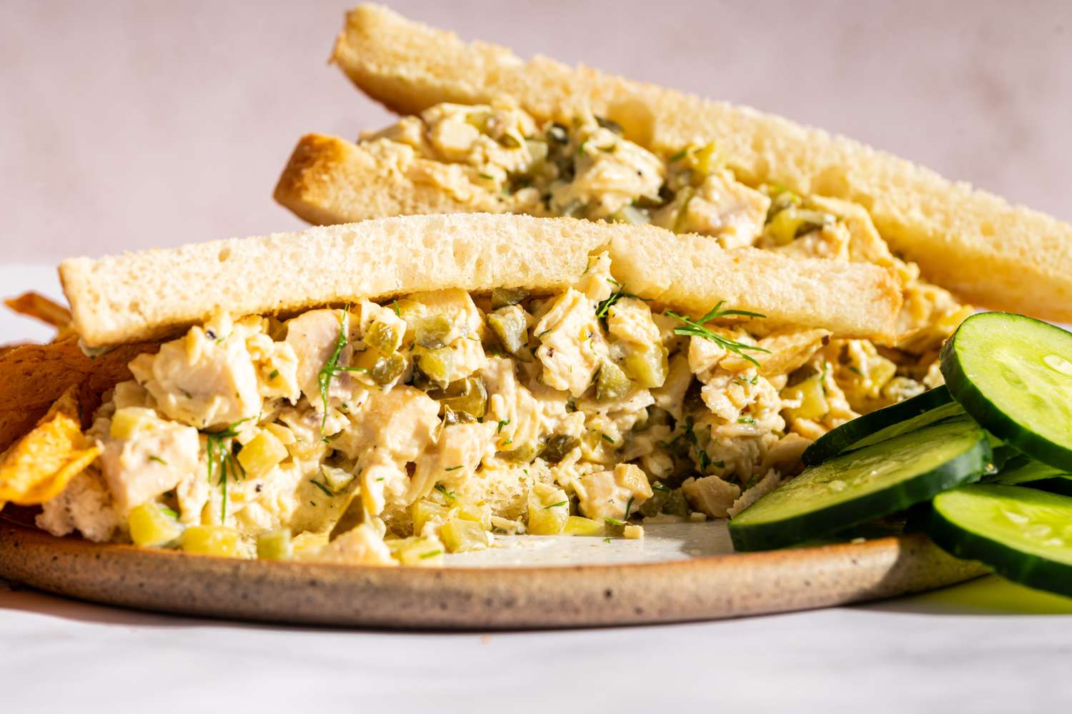 Chicken salad sandwich on a plate with cucumber slices