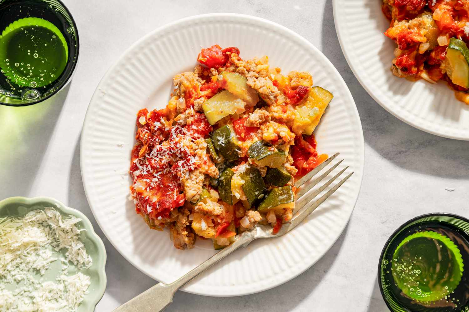 A plate of zucchini pizza bake served with a fork garnished with cheese