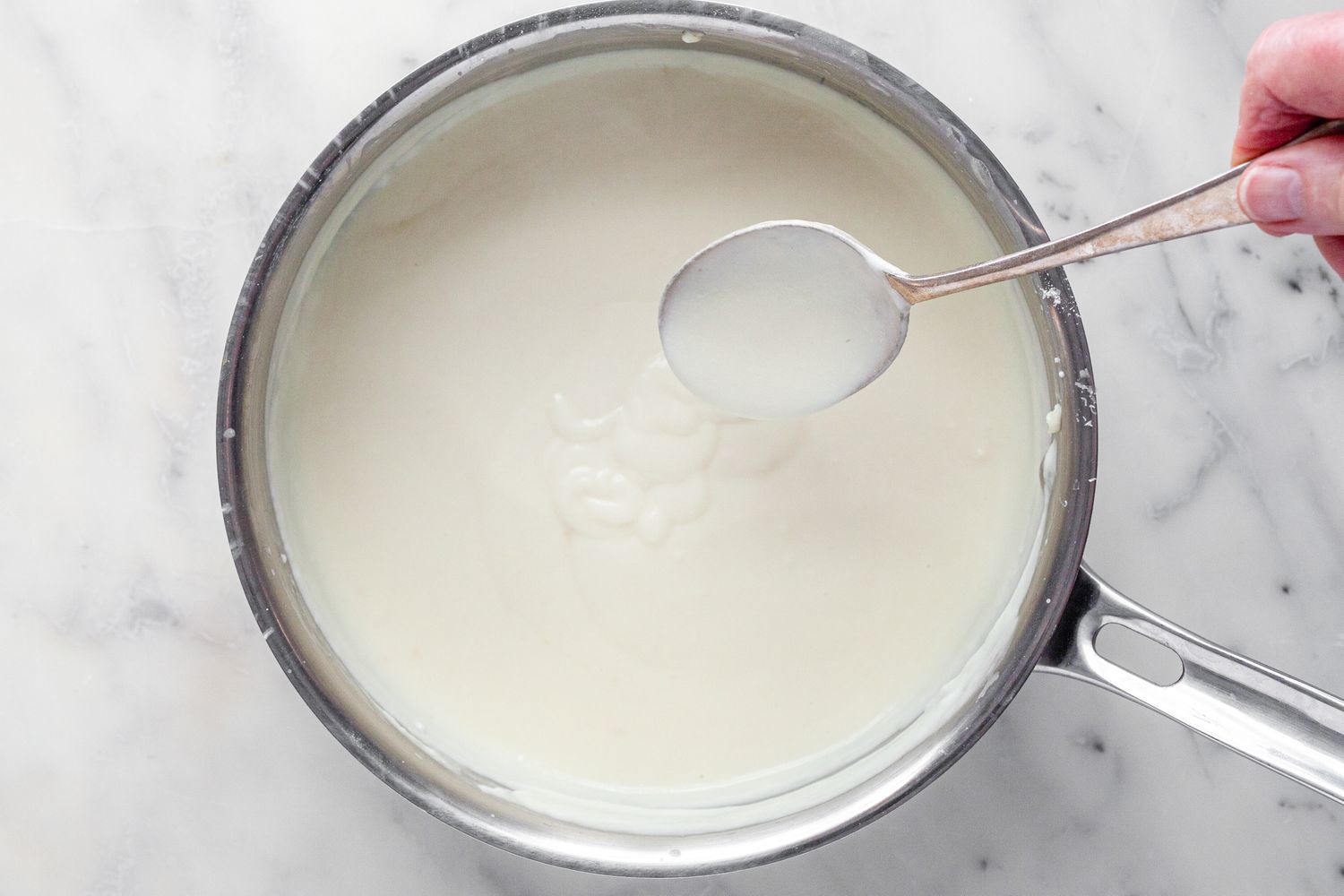 Spoon Used to Check Consistency of White Sauce for Chicken Lasagna