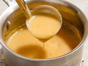 Angled view of a pot of 3-ingredient gravy with a ladle removing a serving