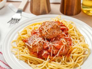 Plate of spaghetti with meatballs and tomato sauce topped with grated cheese