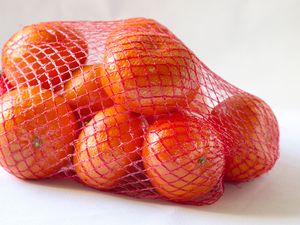 Oranges in a red mesh bag on a white background