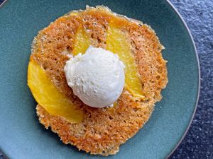 Peach upsidedown cookie topped with a scoop of ice cream on a plate