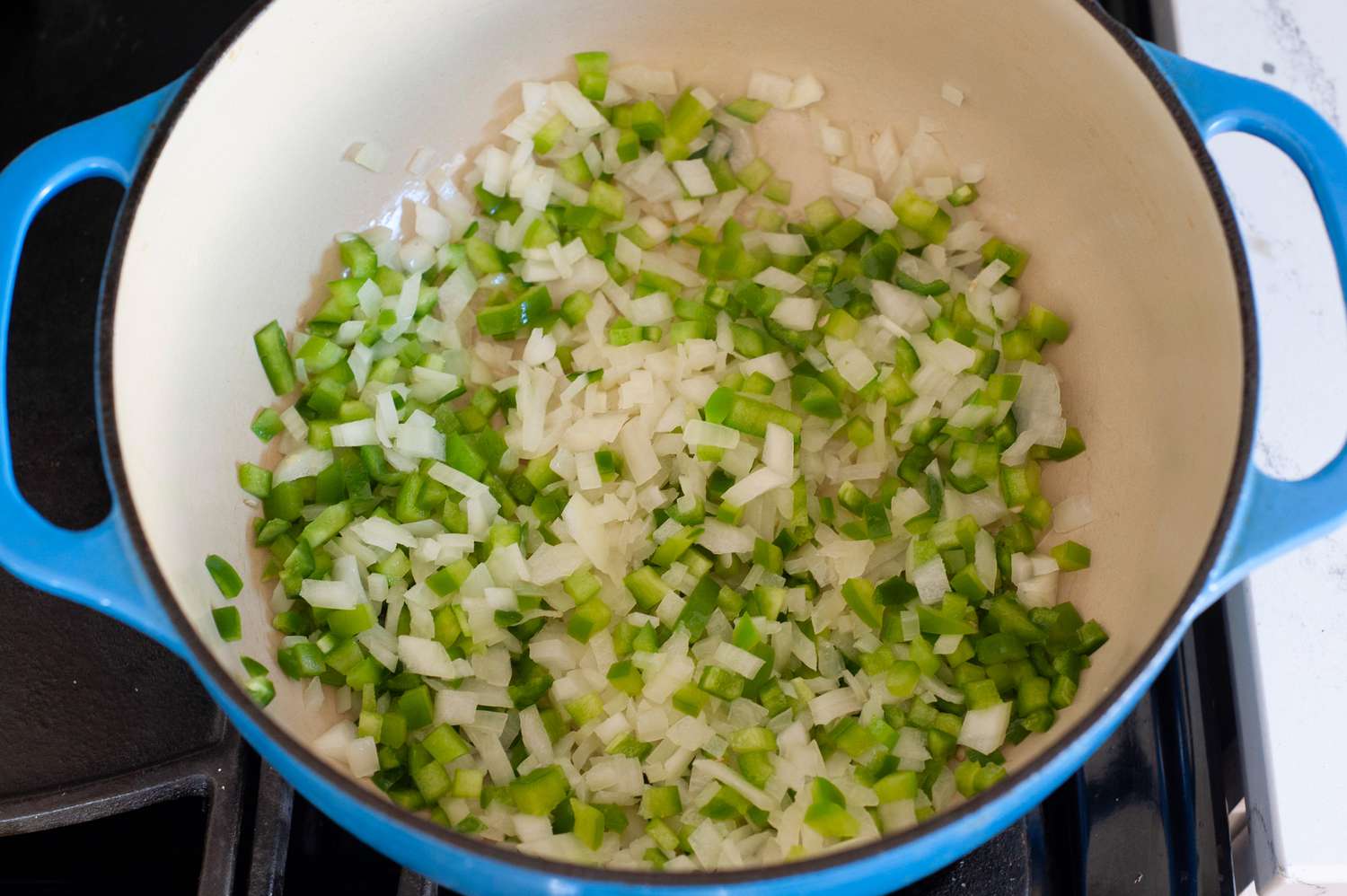 A dutch oven with ingredients sauteing inside to make vegetarian-friendly tortilla soup