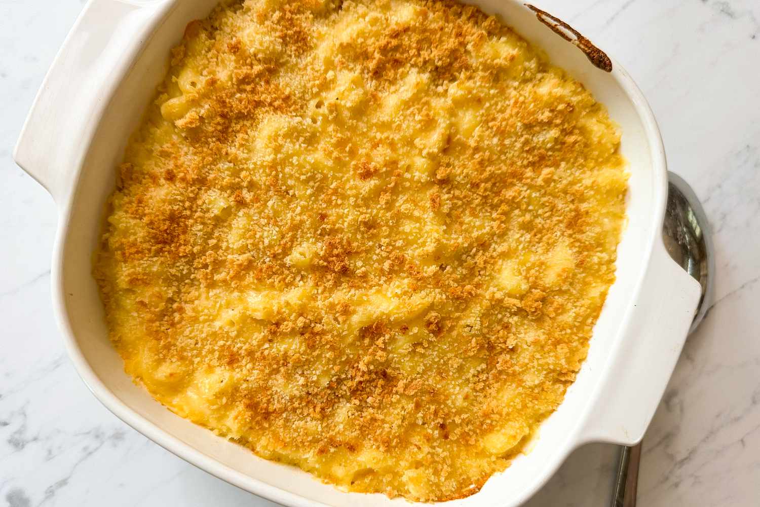 Overhead view of a baking dish of macaroni and cheese on a marble countertop