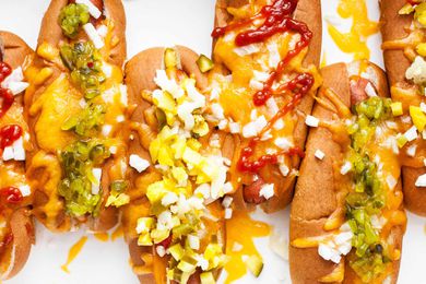 Hot dogs topped with melted cheese, diced onions, relish, and ketchup