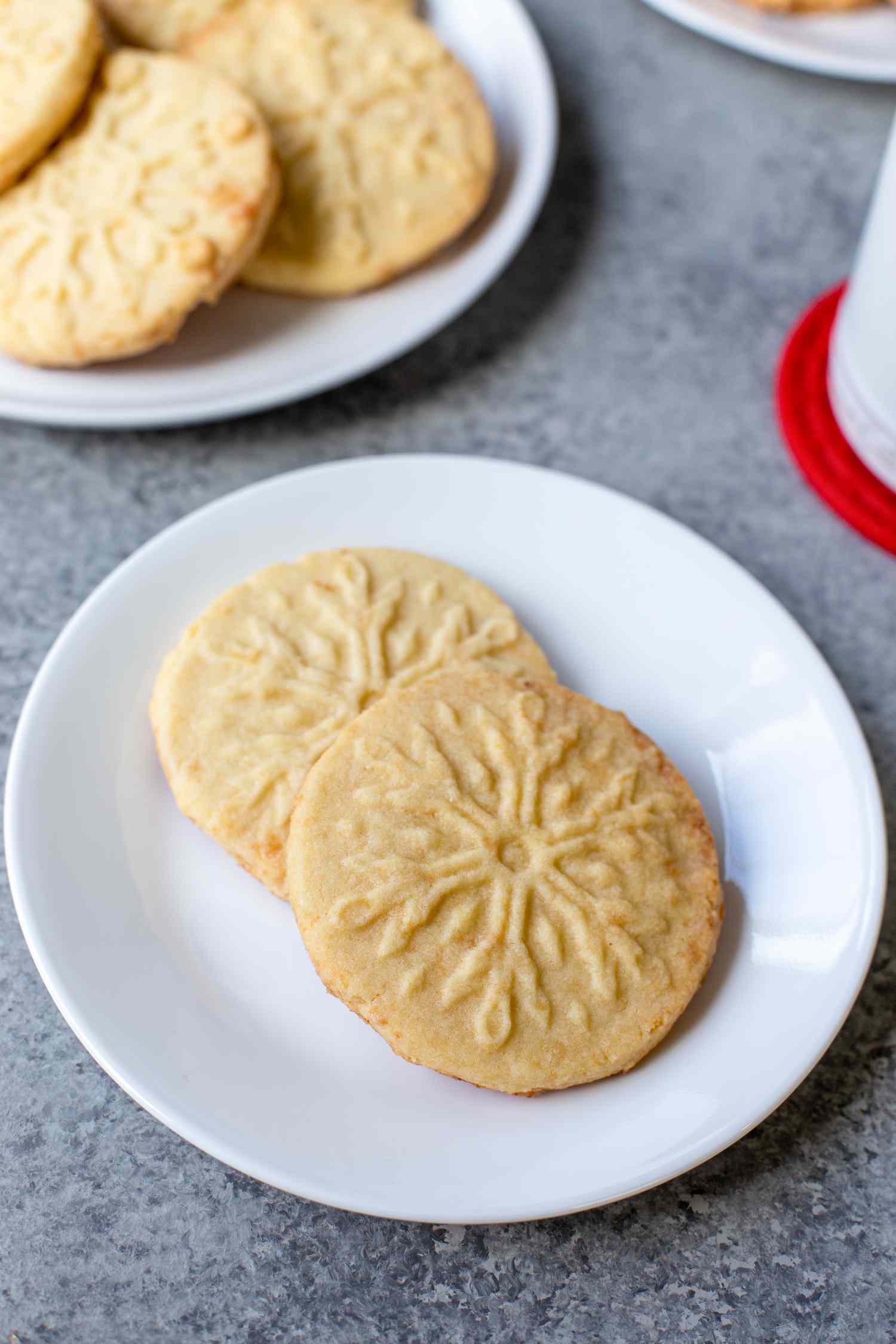 Almond shortbread cookies on a white plate with a second plate behind it.