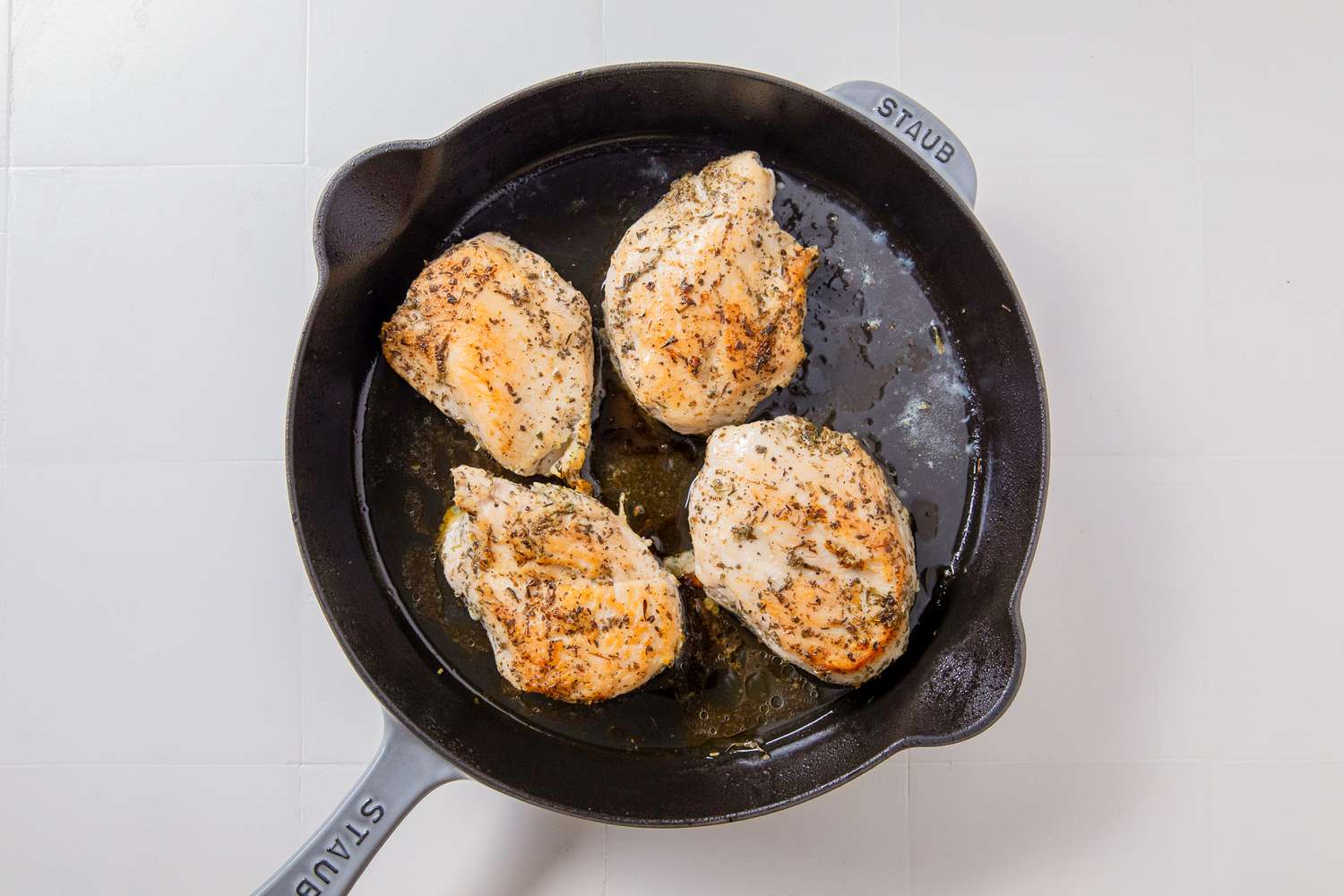 Overhead view of chicken breasts cooking in a cast iron skillet for Marry Me Chicken Casserole recipe