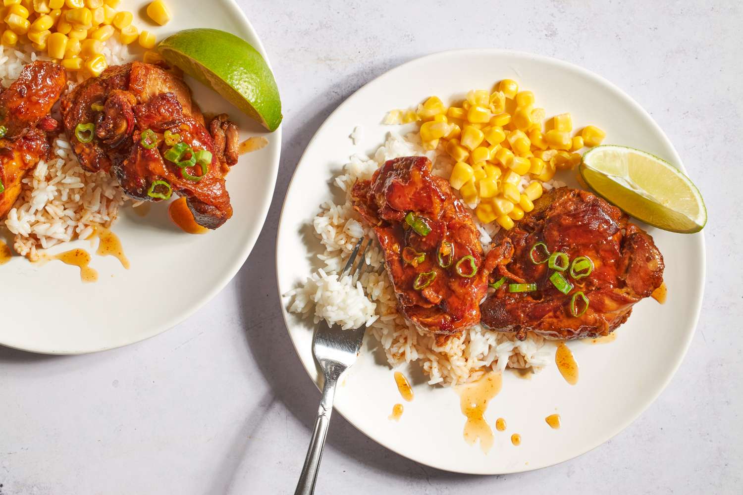 Plates of hot honey chicken served with rice corn and lime wedges