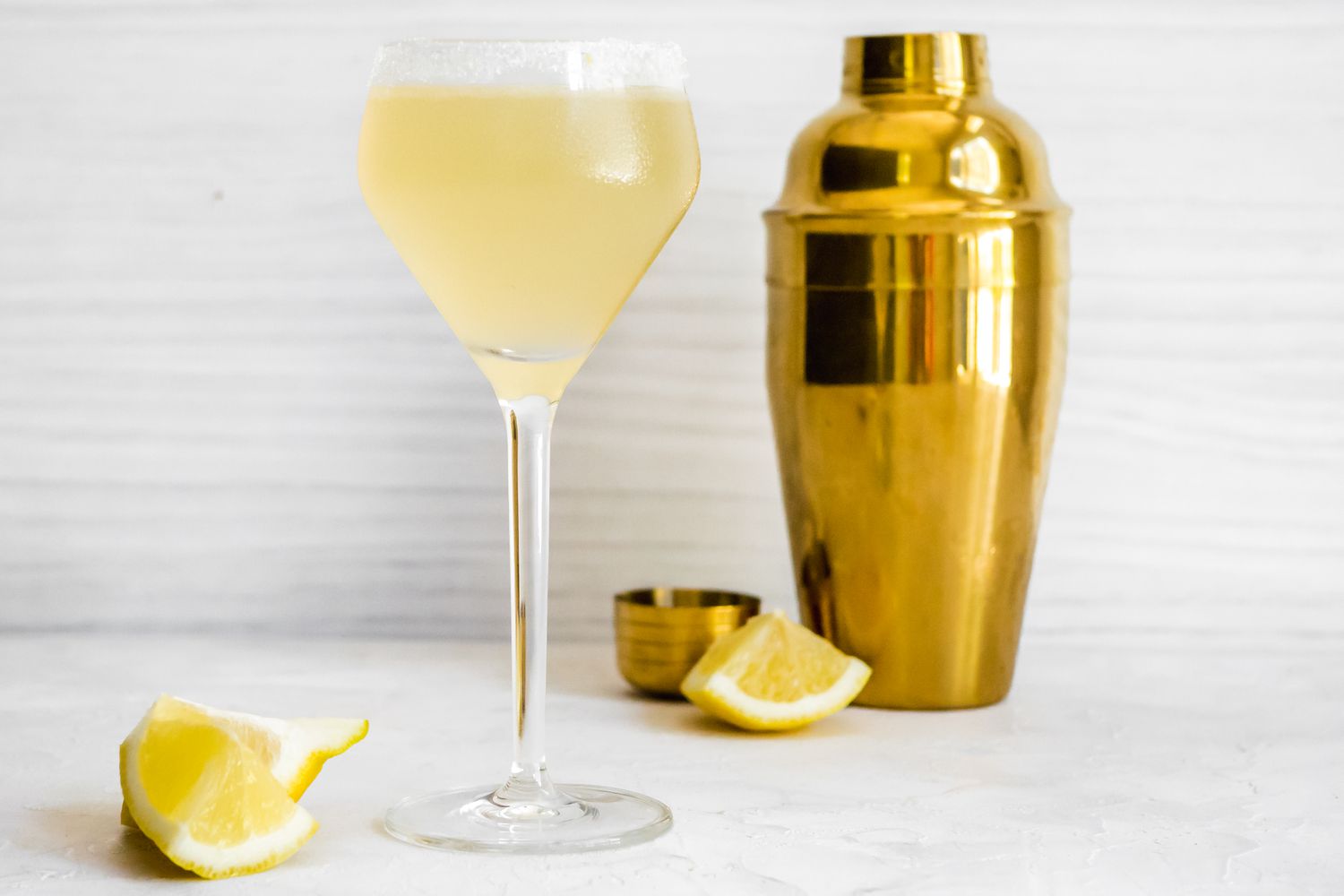 Lemon Drop Martini Next to Lemon Wedges and a Shaker