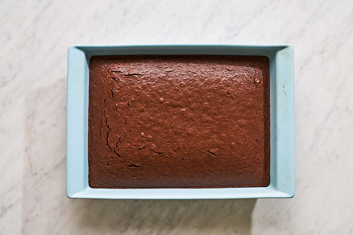 Overhead view of a light blue baking dish of the batter after baking for Mississippi Mud Cake recipe