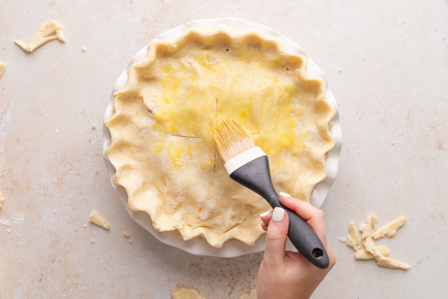 Brushing the top crust of an easy peach raspberry pie before baking.