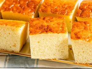 Several slices of spongy condensed milk cake on a beige background