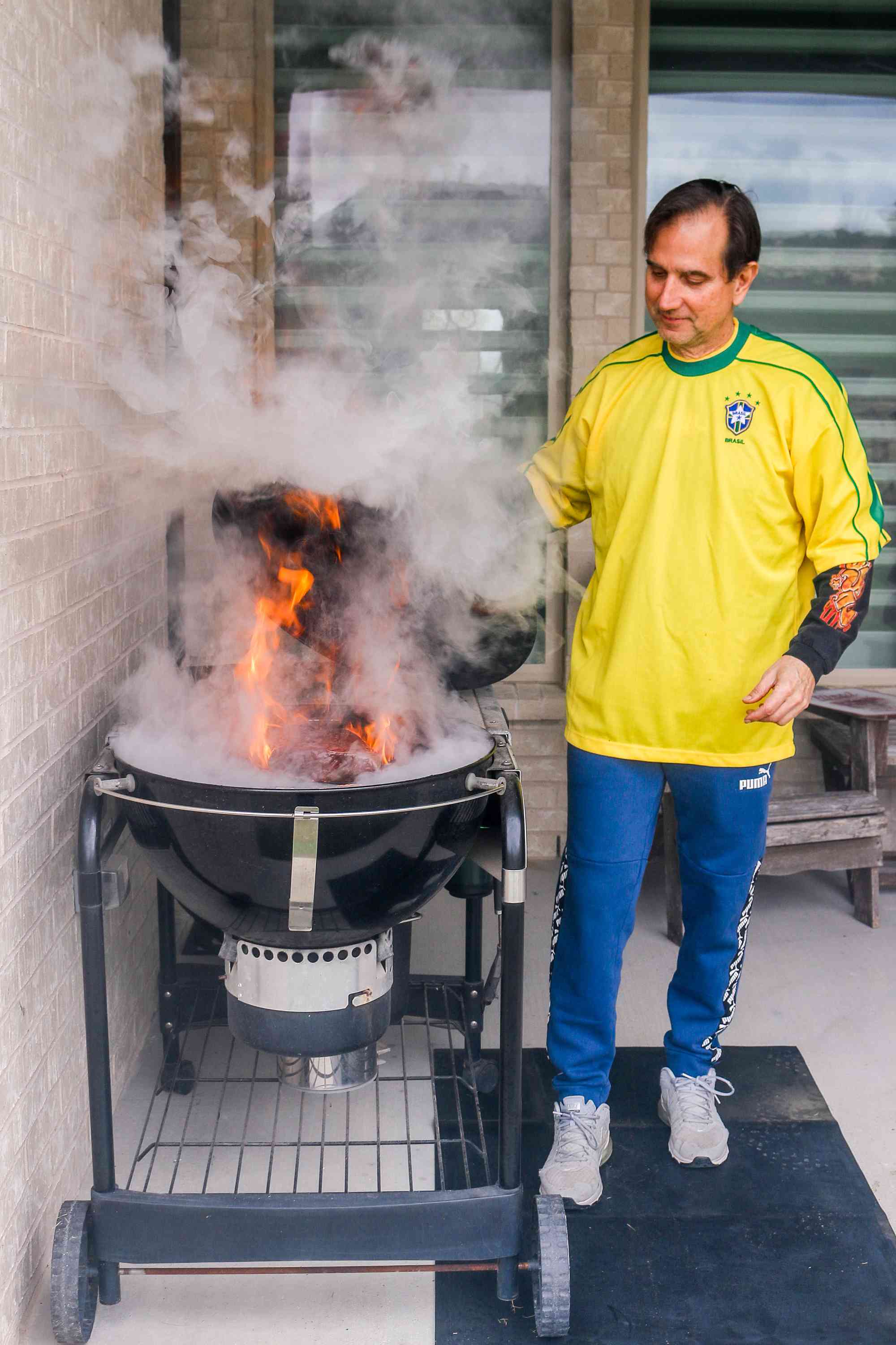 Flames and smoke rise from the grill as Plinio Monteiro cooks picanha outdoors