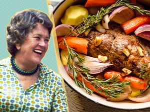 Julia Child smiling next to a pot roast with vegetables
