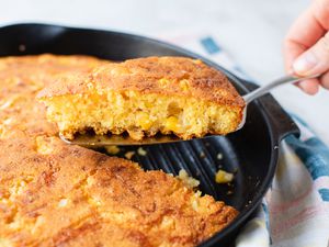 A Serving of Cheesy Skillet Cornbread Lifted from Skillet of More Cornbread