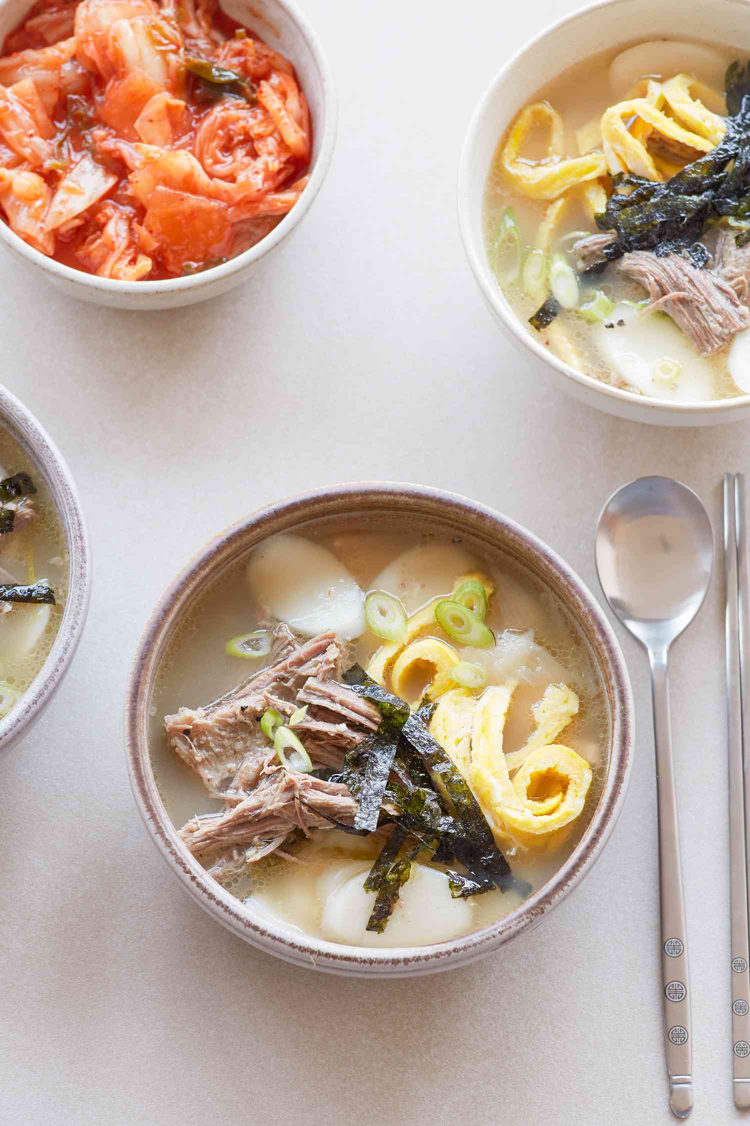 Overhead view of Korean rice cake soup on a table with a spoon.