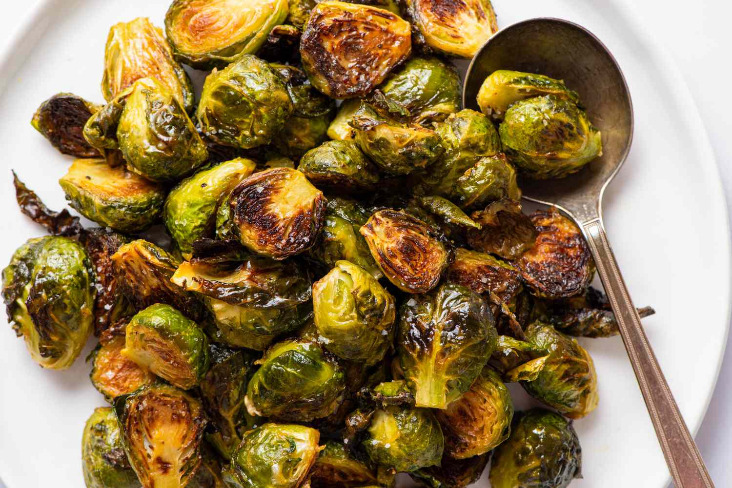 A closeup of honey mustard roasted Brussels sprouts on a white serving plate