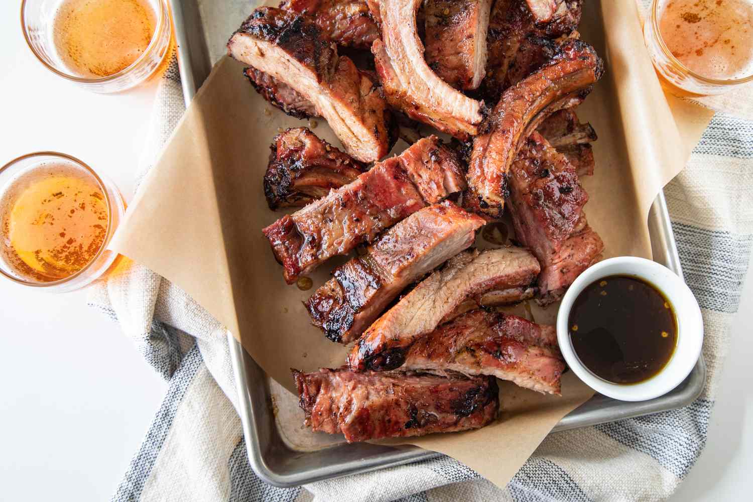 A parchment lined baking sheet with cut ribs from a grilled ribs recipe.