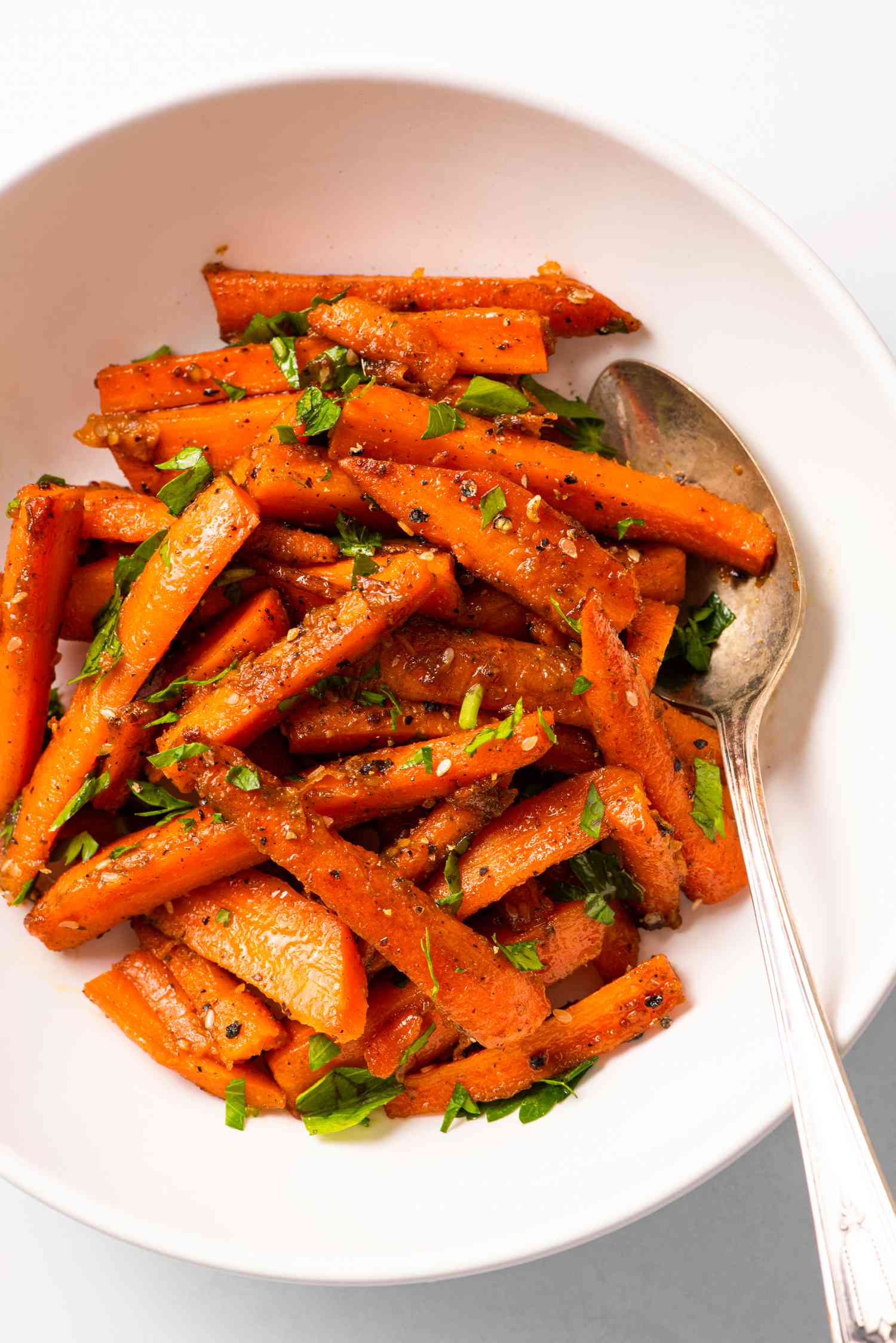4-ingredient honey-glazed carrots in a white bowl with a spoon