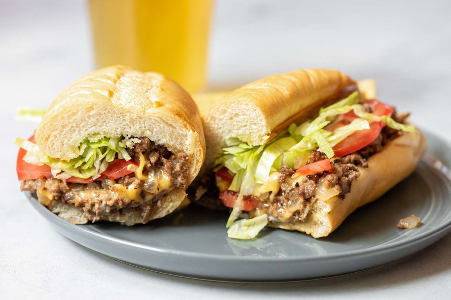 Two Halves of a Chopped Cheese Sandwich on a Plate 