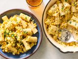 A bowl and a skillet with cooked pasta mixed with corn and garnished with herbs