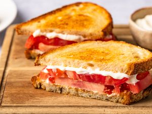 A sandwich with sliced tomatoes and mayonnaise on toasted bread