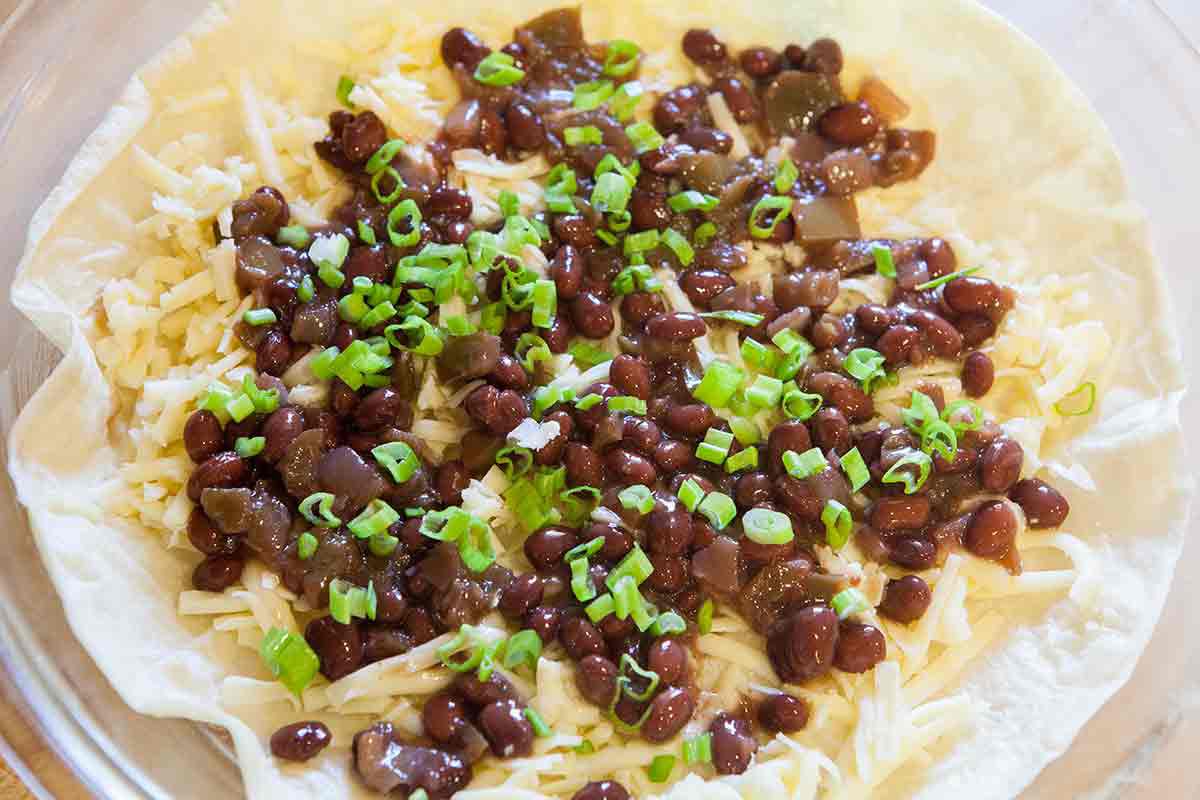 layer black beans on tortilla with cheese in quesadilla pie