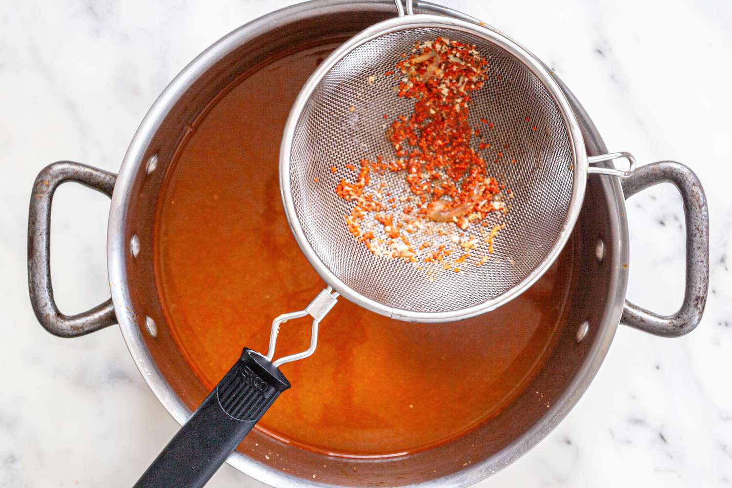 Broth Strained Again to Remove Lobster Shells Using a Fine Mesh Strainer