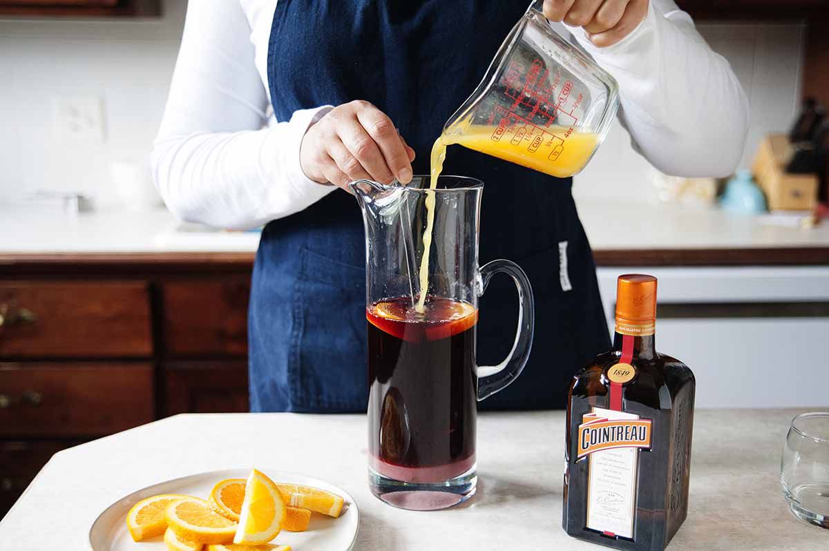 Red Wine Sangria Recipe - orange slices in a pitcher of sangria on a silver tray with two poured glasses of sangria