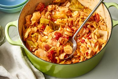 Angled view of a green dutch oven of swamp cabbage with a metal serving spoon