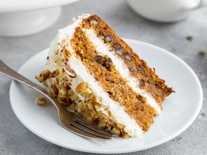 Closeup shot of a slice of layer carrot cake with cream cheese frosting on a plate