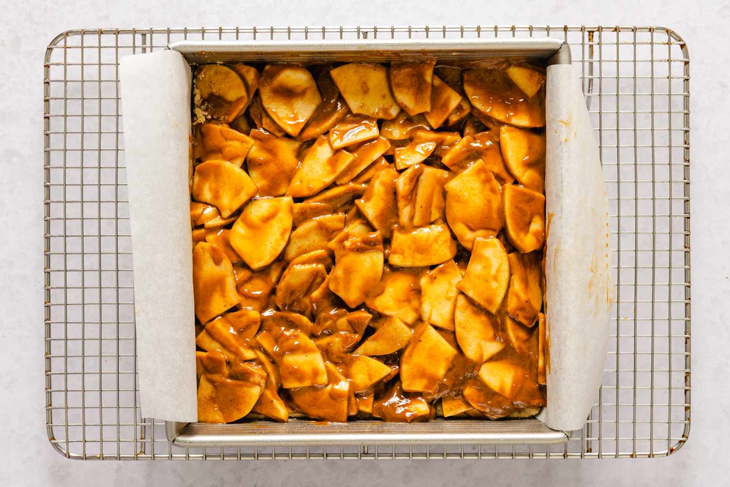 Tray of caramel apple bars cooling on a rack topped with baked apple slices and caramel sauce for caramel apple bars recipe