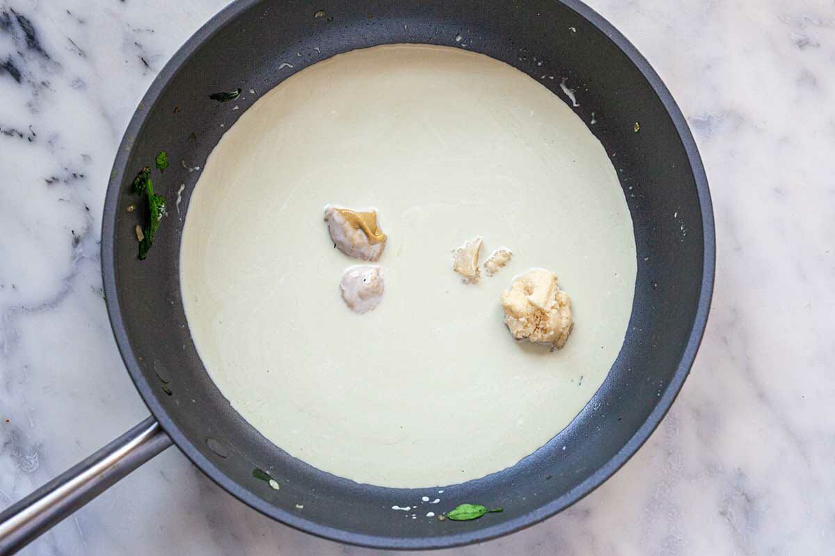 Sauce ingredients in the bottom of the skillet for a Homemade Creamed Spinach recipe.