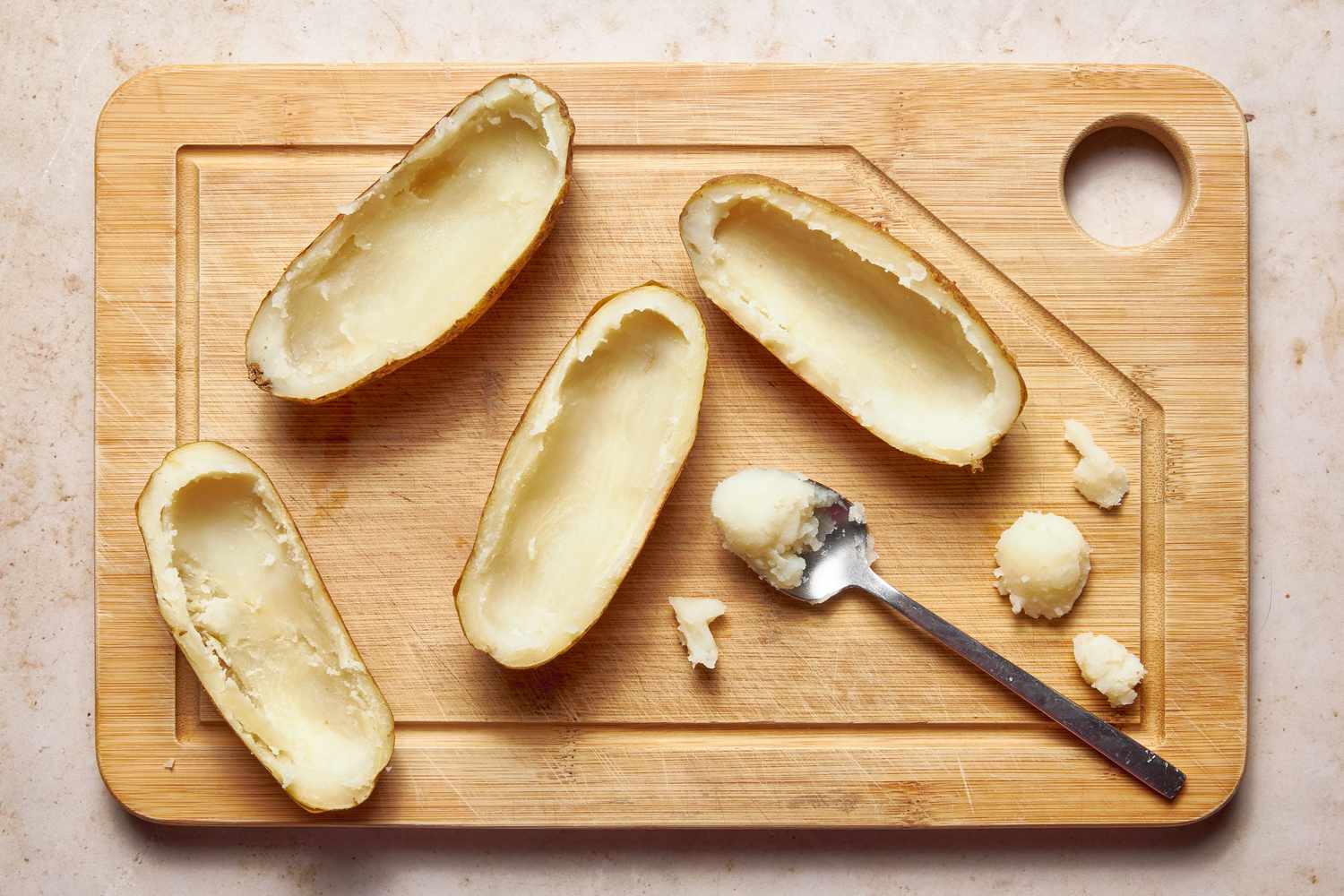 Insides of baked potatoe halves scooped out using a spoon for twice baked potatoes recipe