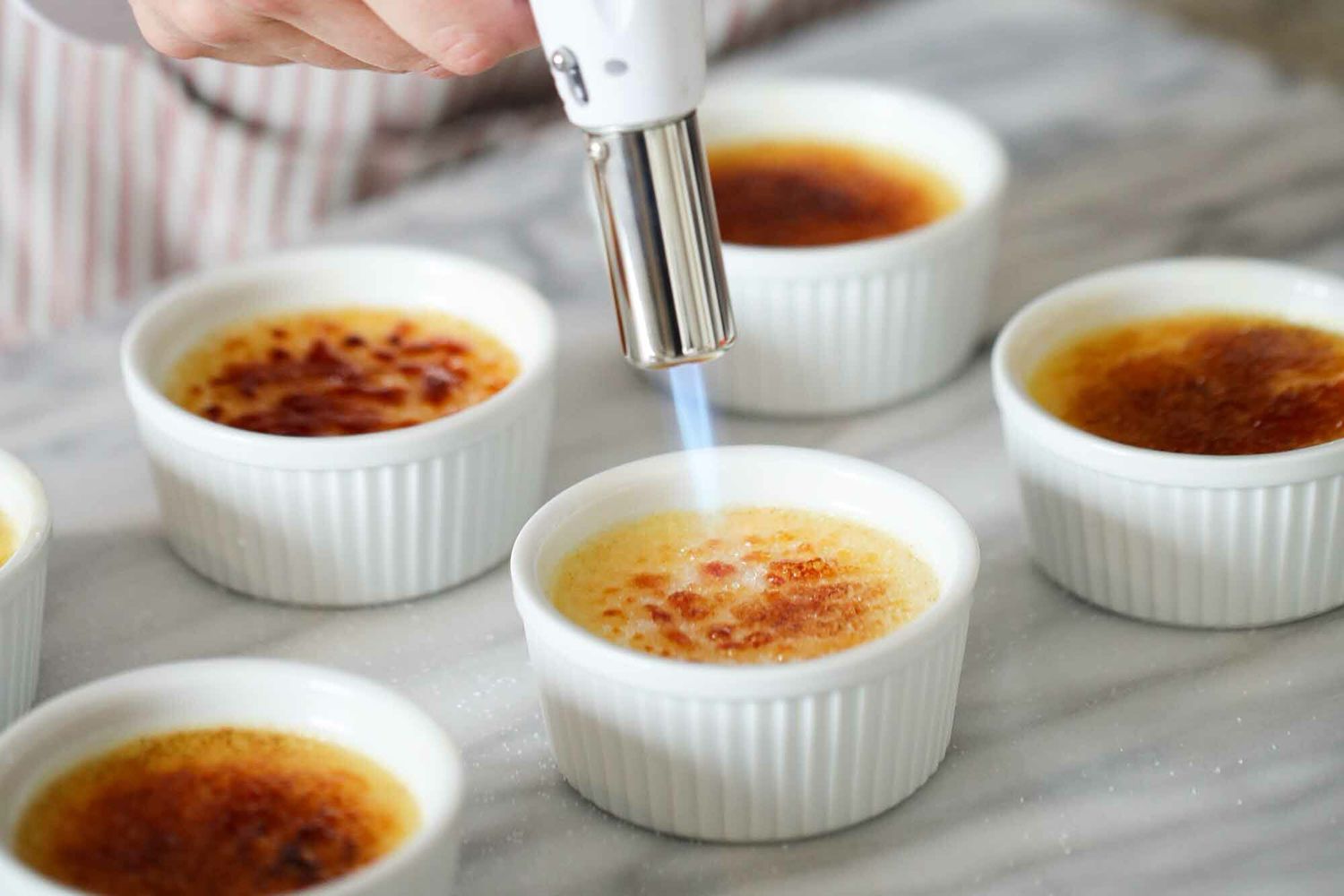 A torch browning the tops of the custards