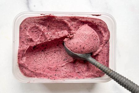 Frozen yogurt being scooped from a container with a metal ice cream scoop