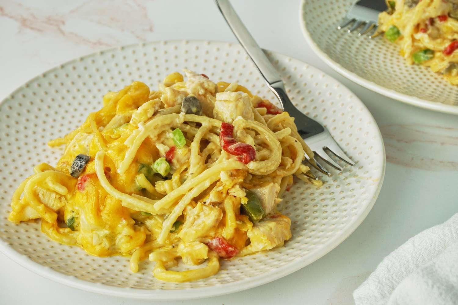 A plate of Ree Drummond's Chicken Spaghetti with vegetables on a table with a fork