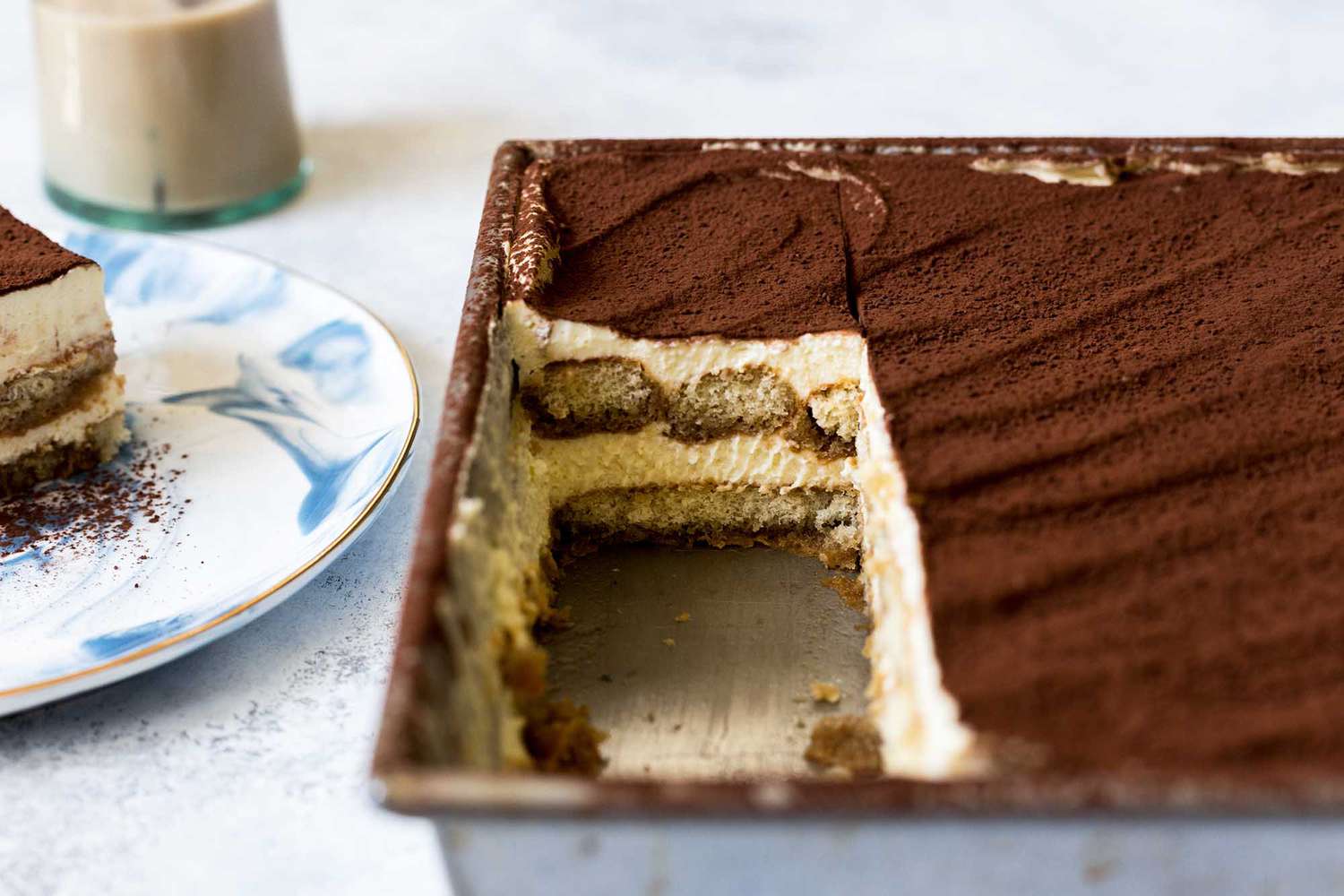 Cross-section of a pan of tiramisu with pieces removed from the pan