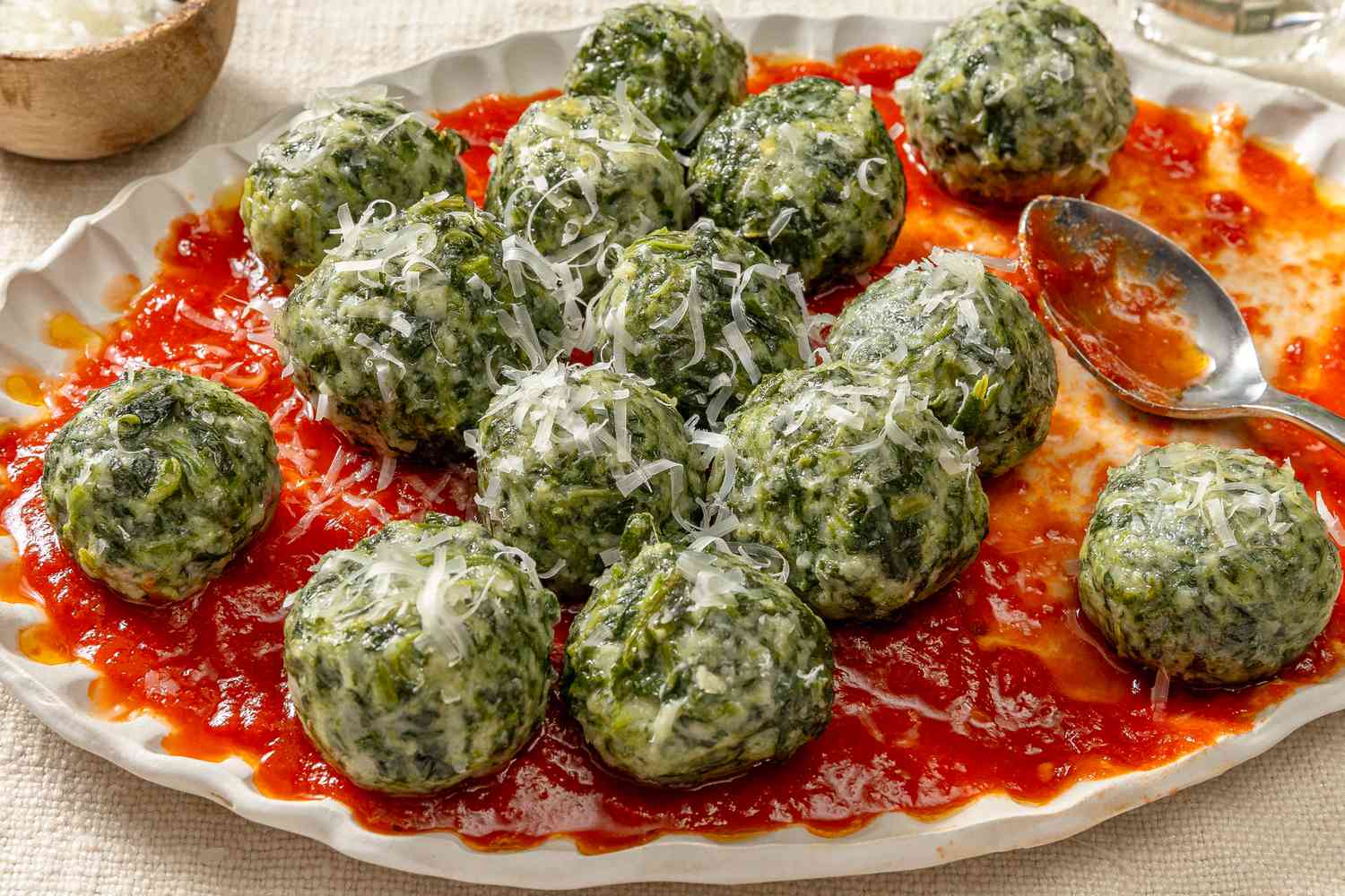 Angled view of a plate of ravioli gnudi over marinara sauce with a spoon