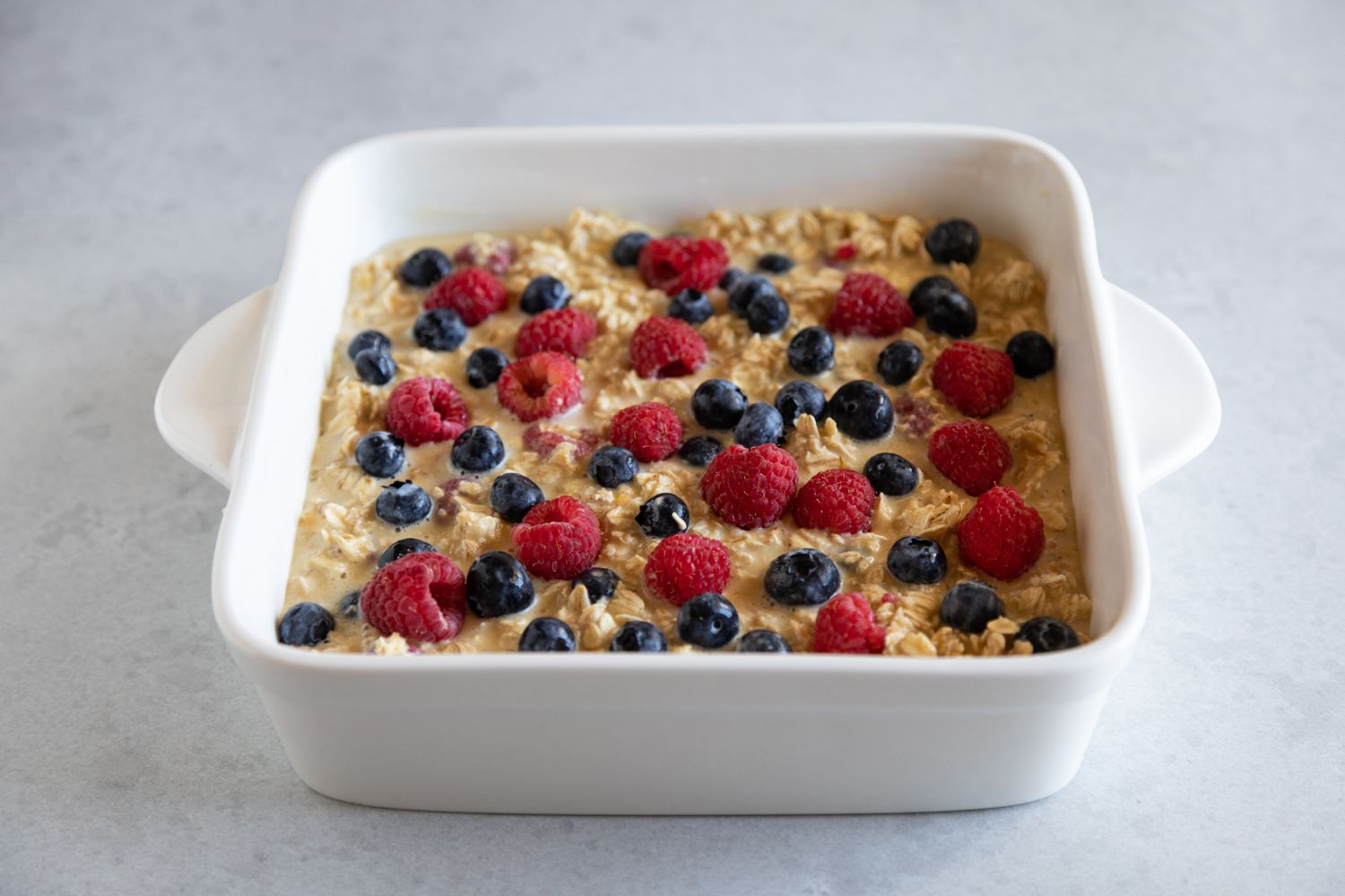 Mixed Berry Baked Oatmeal in a ceramic baking dish and ready to be baked.